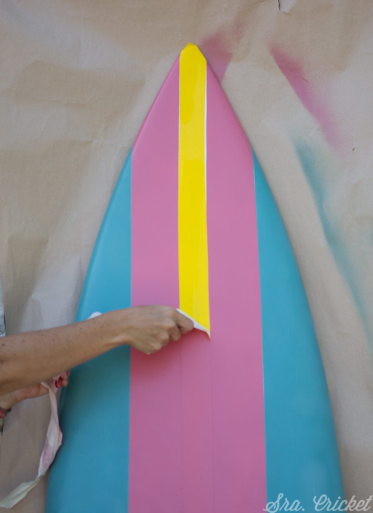 peeling masking tape on spray painted surf board